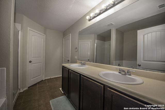 bathroom with vanity, tile patterned flooring, a shower with door, and a textured ceiling