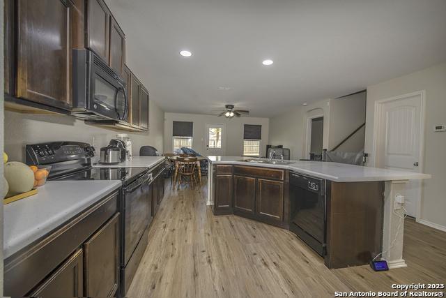 kitchen with black appliances, sink, ceiling fan, light hardwood / wood-style floors, and dark brown cabinetry