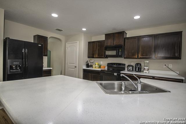 kitchen with dark brown cabinetry, sink, and black appliances