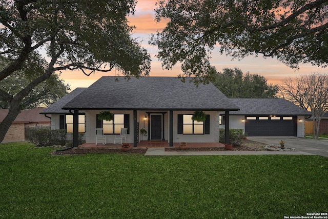 view of front of home with a garage, a porch, and a yard