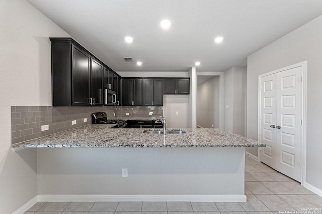 kitchen featuring appliances with stainless steel finishes, kitchen peninsula, sink, and light stone countertops