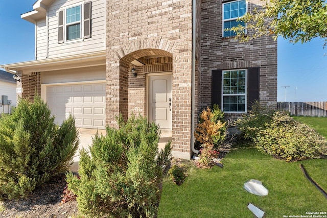 view of exterior entry featuring a garage and a lawn