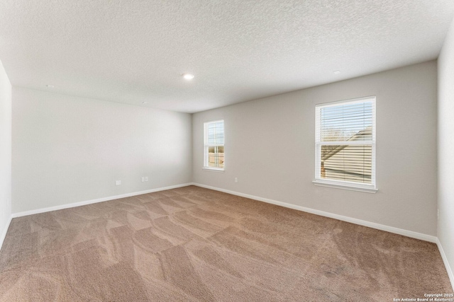 empty room with light colored carpet and a textured ceiling