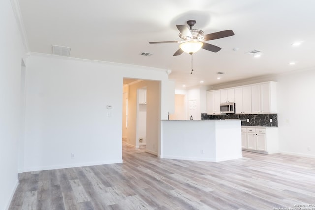 kitchen featuring tasteful backsplash, white cabinetry, light wood-type flooring, and kitchen peninsula