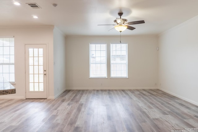 empty room featuring crown molding, light hardwood / wood-style floors, and a wealth of natural light