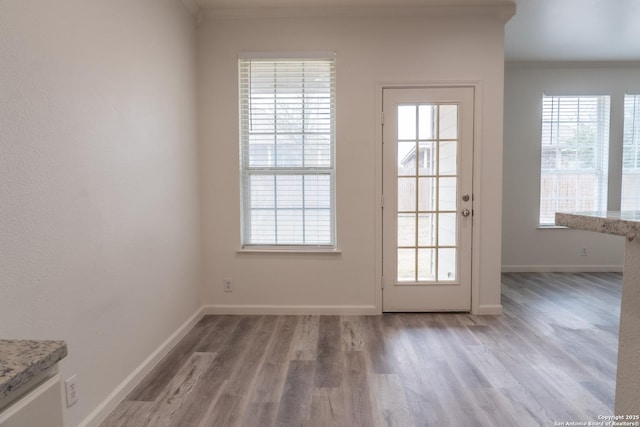 doorway to outside with wood-type flooring and crown molding