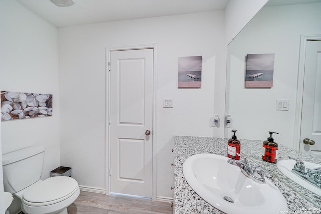 bathroom with wood-type flooring, toilet, and vanity