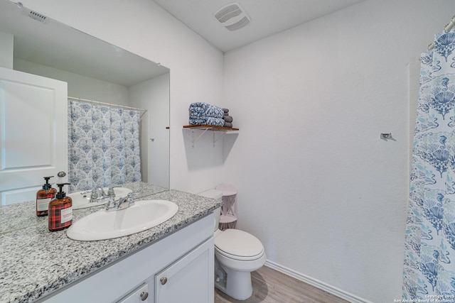 bathroom with wood-type flooring, curtained shower, vanity, and toilet