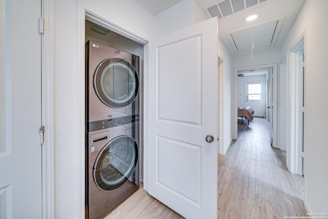 washroom with stacked washer / drying machine and light wood-type flooring