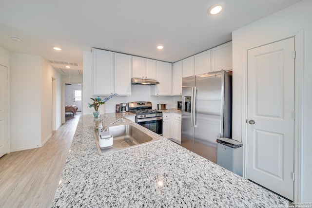 kitchen featuring sink, appliances with stainless steel finishes, kitchen peninsula, light hardwood / wood-style floors, and white cabinets