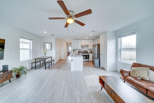 living room featuring ceiling fan, sink, and light wood-type flooring