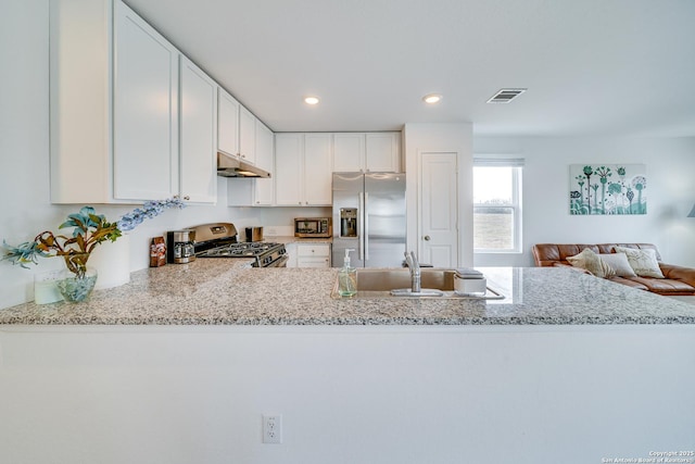 kitchen featuring sink, light stone counters, appliances with stainless steel finishes, kitchen peninsula, and white cabinets