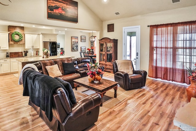 living room featuring high vaulted ceiling and light hardwood / wood-style flooring