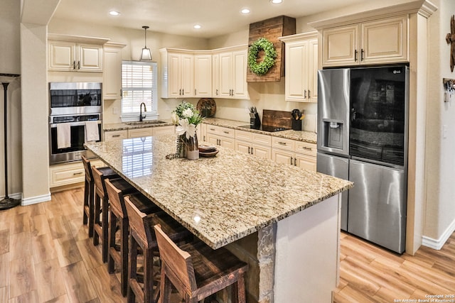 kitchen with a breakfast bar, sink, hanging light fixtures, a center island, and stainless steel appliances