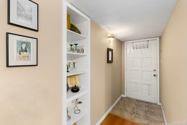 doorway with hardwood / wood-style flooring, built in features, and a textured ceiling