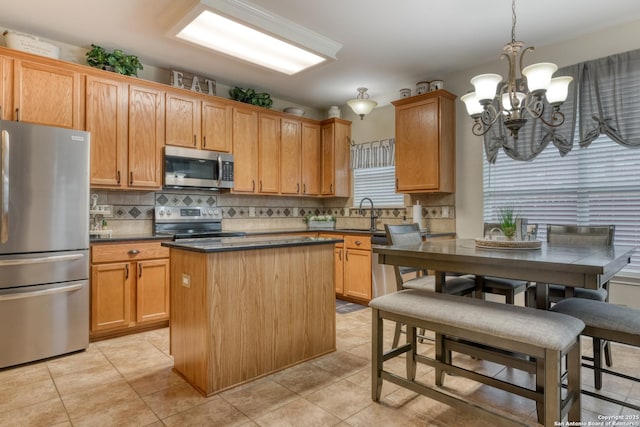 kitchen featuring decorative light fixtures, a center island, light tile patterned floors, appliances with stainless steel finishes, and backsplash