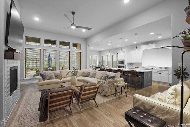 living room with ceiling fan, a healthy amount of sunlight, a fireplace, and light hardwood / wood-style flooring