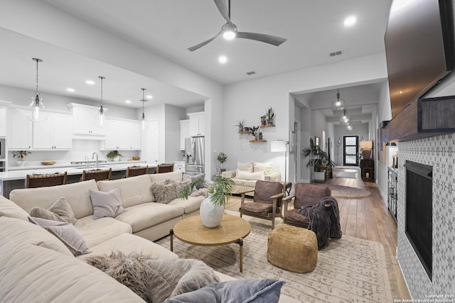 living room with ceiling fan, sink, and light wood-type flooring