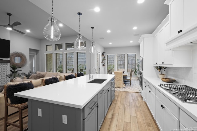 kitchen featuring sink, gray cabinetry, a center island with sink, stainless steel appliances, and white cabinets