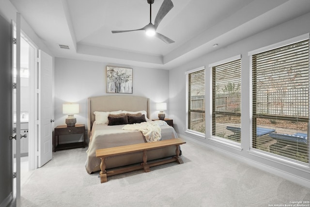 carpeted bedroom featuring a raised ceiling and ceiling fan