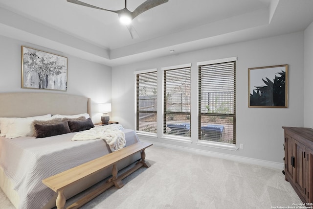 carpeted bedroom featuring ceiling fan and a raised ceiling