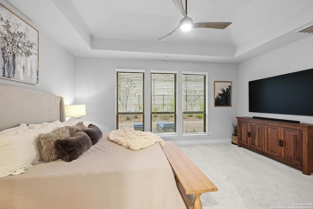 carpeted bedroom with a tray ceiling and ceiling fan