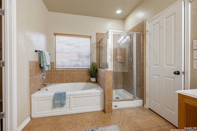 full bathroom featuring tile patterned flooring, a shower stall, a textured ceiling, and a bath