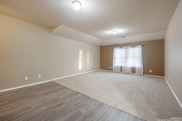 spare room featuring a textured ceiling, wood finished floors, visible vents, and baseboards