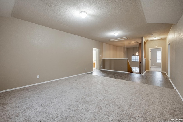 unfurnished room featuring a textured ceiling, a textured wall, dark carpet, and baseboards