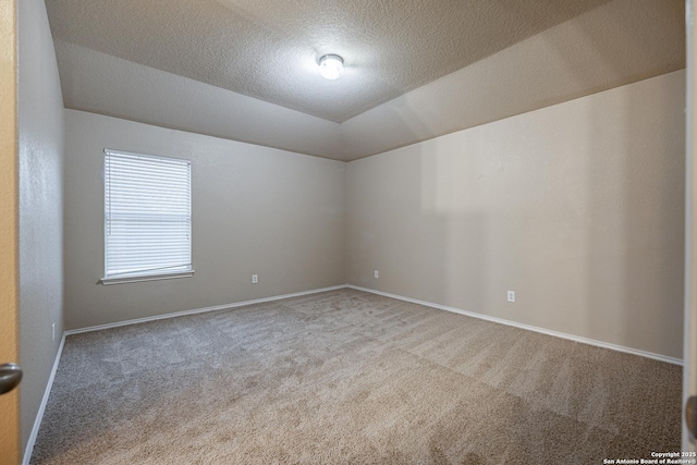 carpeted spare room with vaulted ceiling, a textured ceiling, and baseboards