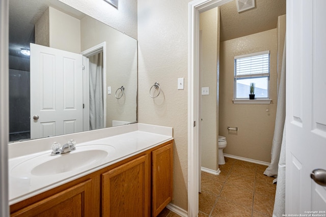 bathroom featuring visible vents, toilet, vanity, tile patterned flooring, and baseboards