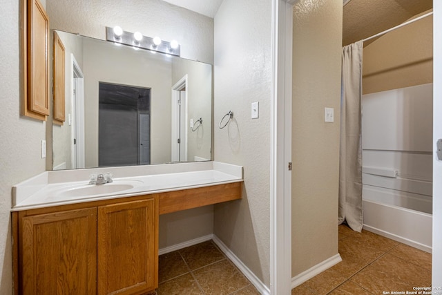 bathroom featuring tile patterned flooring, baseboards, shower / tub combo, and vanity