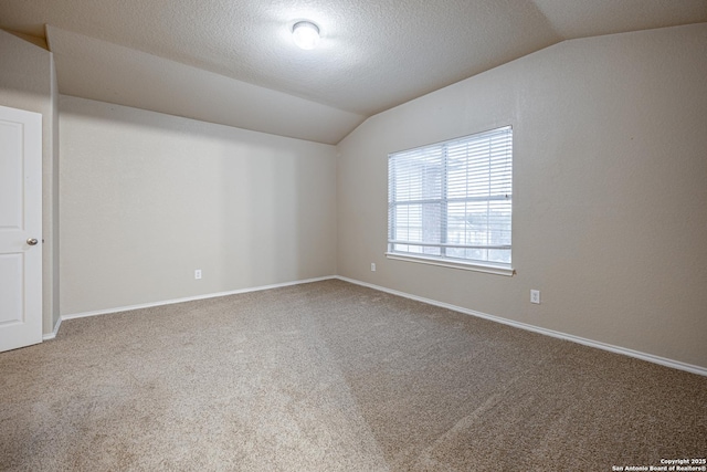 unfurnished room with carpet floors, lofted ceiling, a textured ceiling, and baseboards