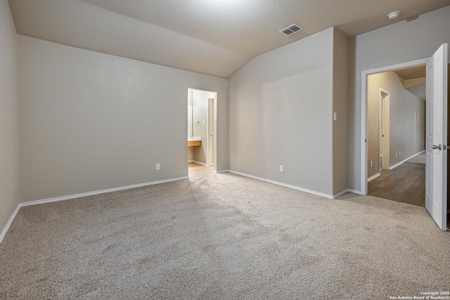 spare room featuring vaulted ceiling, light carpet, visible vents, and baseboards