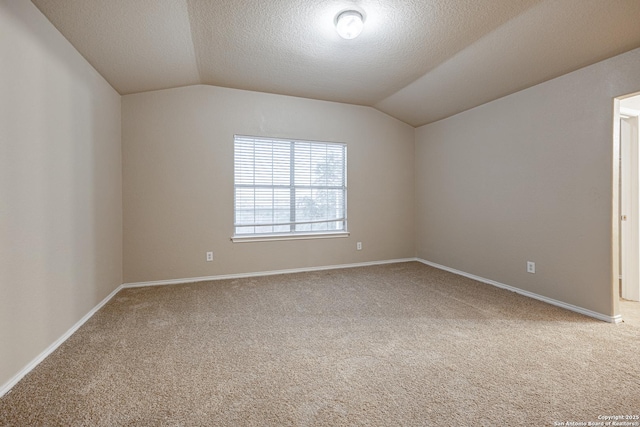 empty room with lofted ceiling, baseboards, carpet floors, and a textured ceiling