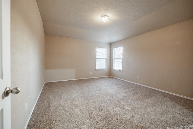 spare room with a textured ceiling, baseboards, and carpet flooring