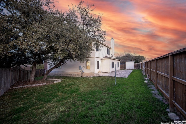 view of yard with a patio area, a fenced backyard, an outdoor structure, and a shed