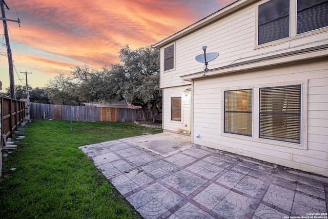 yard at dusk with a patio area and a fenced backyard