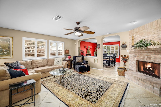 living room featuring light tile patterned floors, a fireplace, and ceiling fan