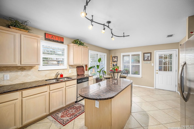 kitchen featuring a kitchen island, appliances with stainless steel finishes, sink, dark stone counters, and light tile patterned floors