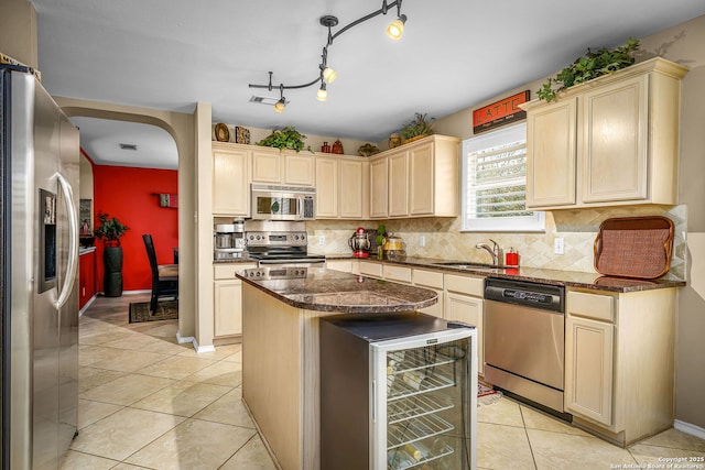 kitchen featuring sink, appliances with stainless steel finishes, a center island, wine cooler, and dark stone counters