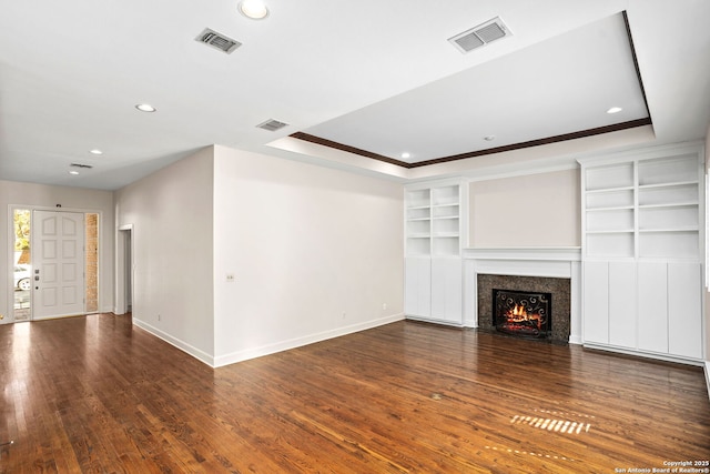 unfurnished living room with a warm lit fireplace, wood-type flooring, visible vents, and baseboards