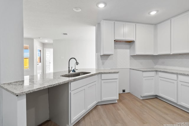 kitchen featuring white cabinetry, sink, light hardwood / wood-style flooring, and kitchen peninsula