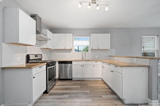 kitchen featuring a peninsula, light stone countertops, stainless steel appliances, and a sink