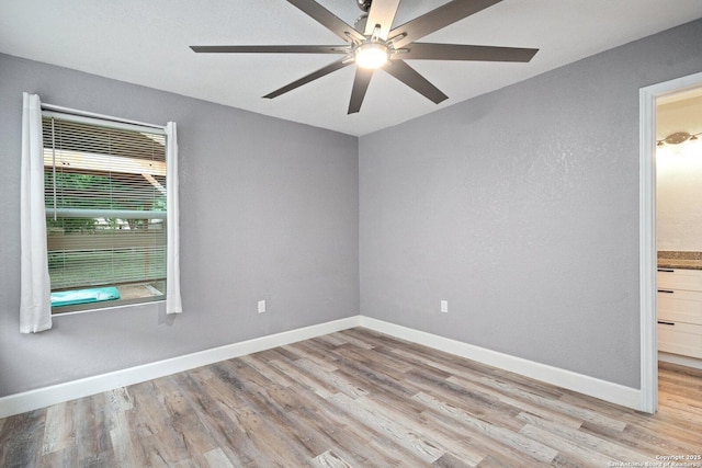 spare room featuring ceiling fan, baseboards, and wood finished floors