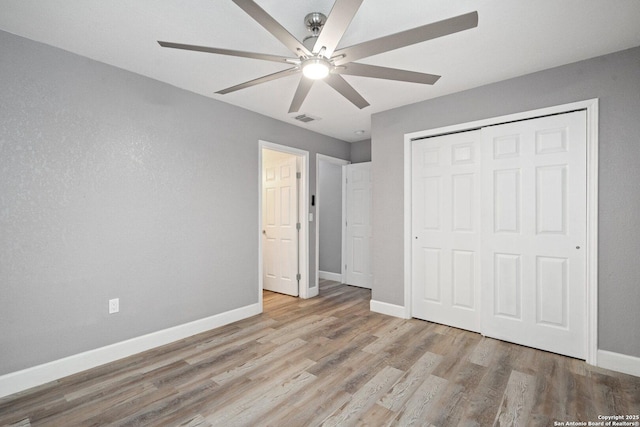 unfurnished bedroom with a ceiling fan, wood finished floors, a closet, baseboards, and visible vents