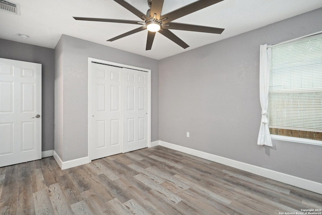 unfurnished bedroom featuring wood finished floors, visible vents, and baseboards