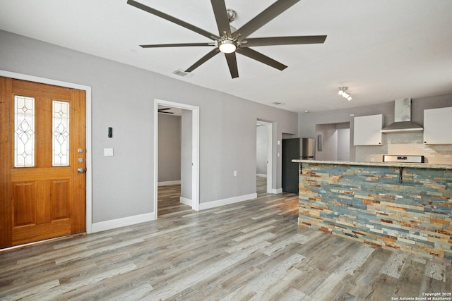 interior space featuring light wood finished floors, visible vents, a ceiling fan, and baseboards