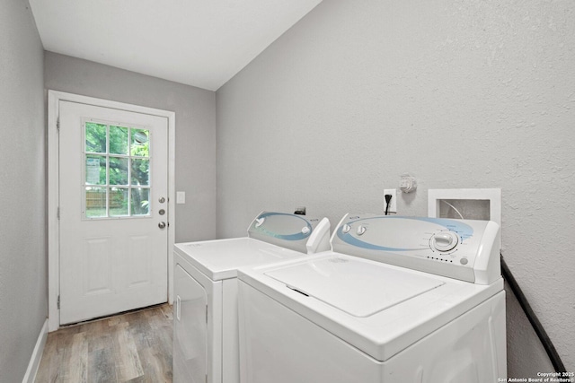washroom with washer and clothes dryer, baseboards, light wood-style floors, a textured wall, and laundry area