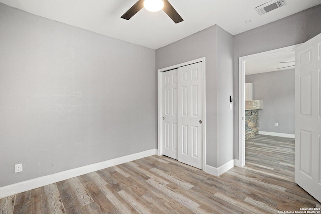 unfurnished bedroom featuring baseboards, visible vents, a ceiling fan, wood finished floors, and a closet